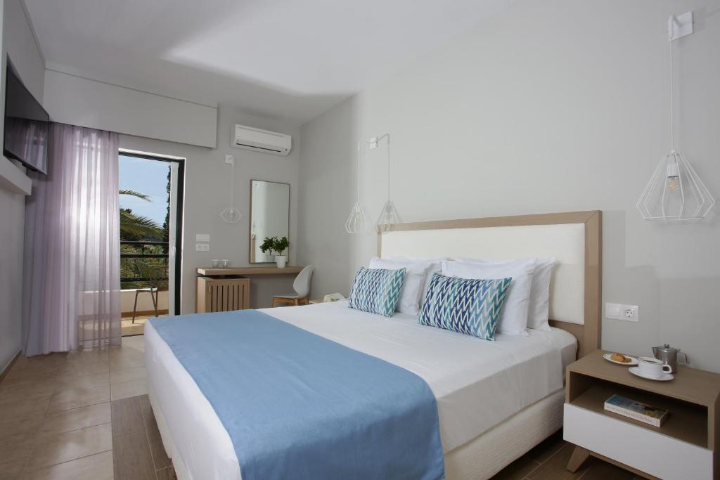 a bedroom with a large white bed with blue sheets at Paradise Hotel Corfu in Gouvia