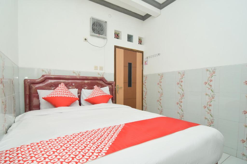 1 dormitorio con 1 cama con almohadas rojas y blancas en Dua Putri Villa en Pasuruan