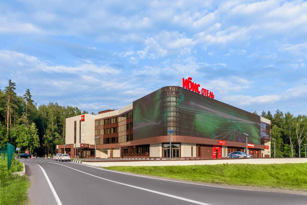a building with people on top of it next to a road at ibis Moscow Domodedovo Airport in Domodedovo