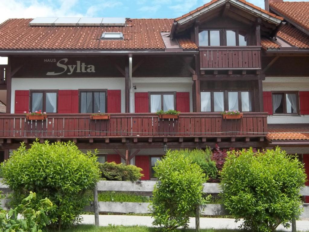 a house with a red and white building with balconies at Haus Sylta in Fischen