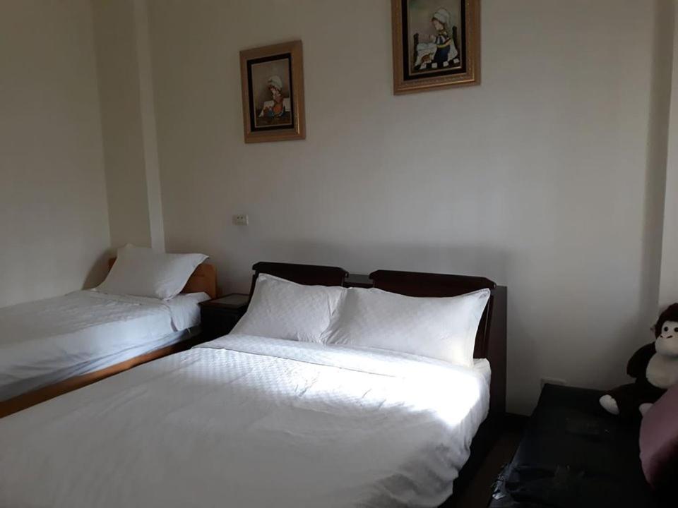 a bedroom with two beds and a teddy bear on a couch at Star 101 Guest House in Taitung City