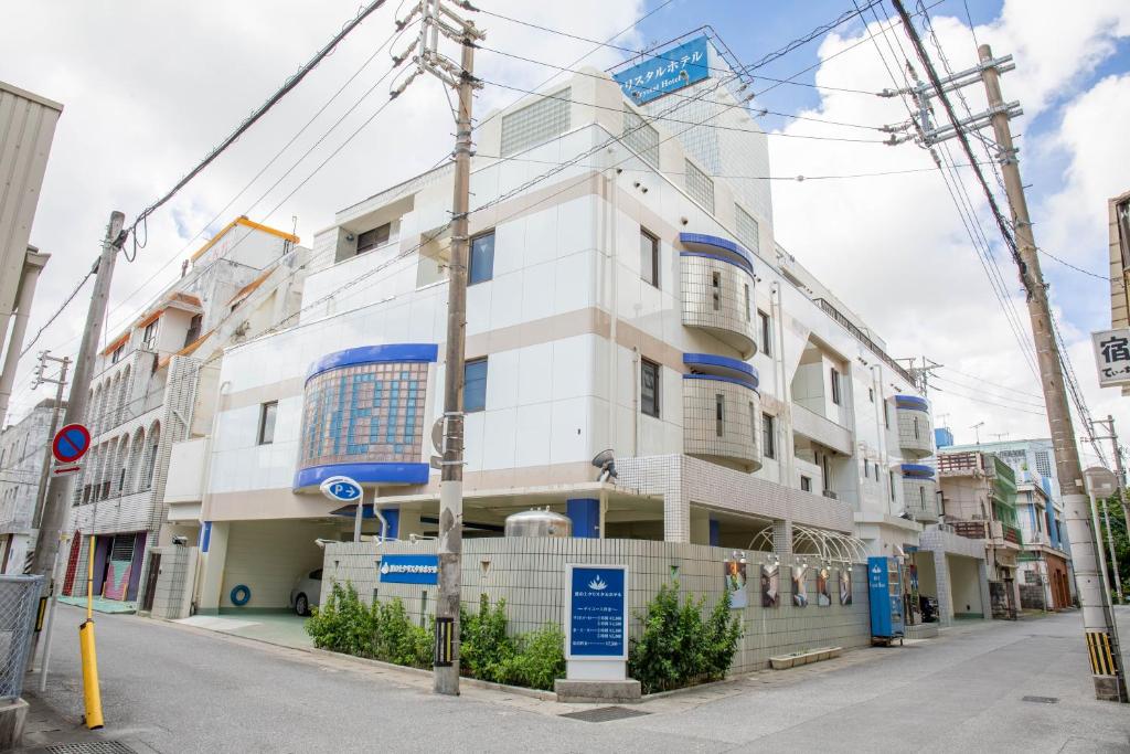 a white building with blue windows on a street at Nami No Ue Crystal Hotel in Naha