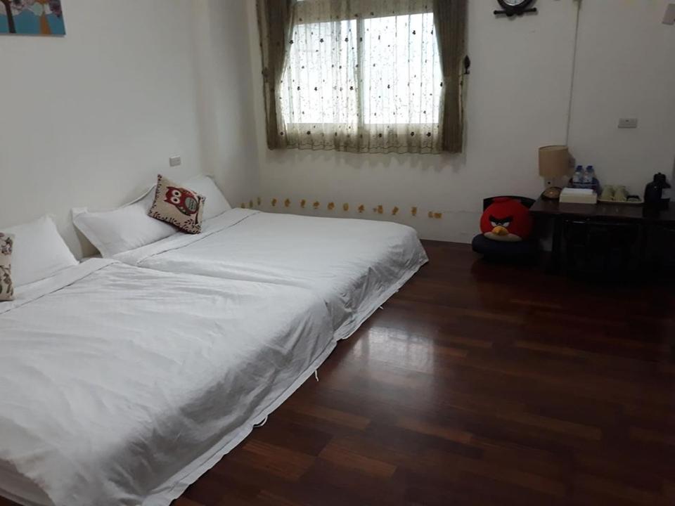 a bedroom with a white bed and a wooden floor at Star 101 Guest House in Taitung City