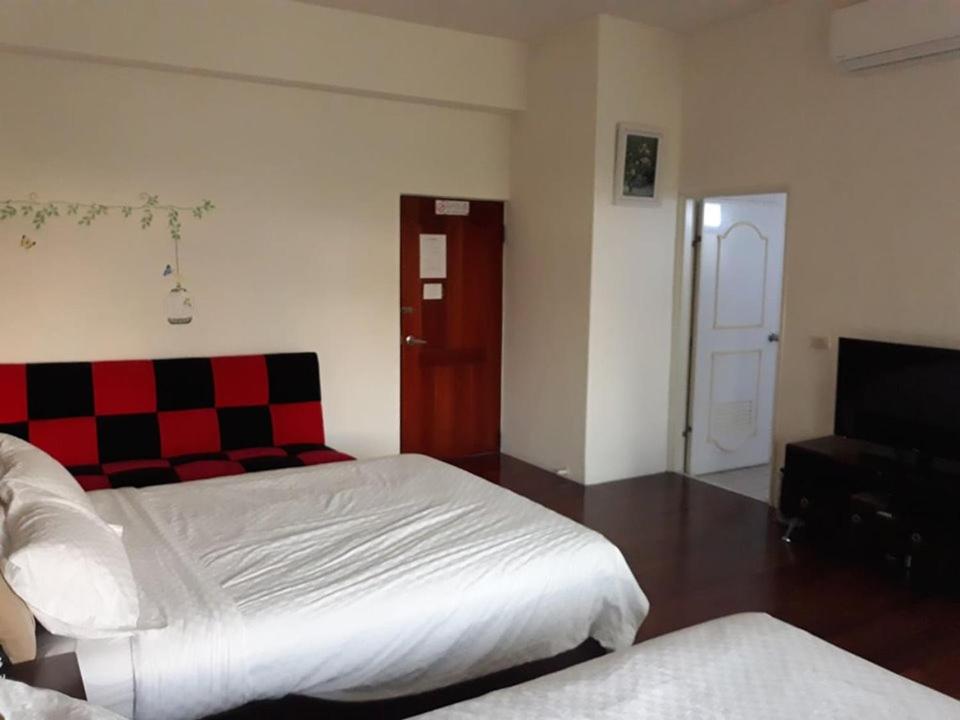 a bedroom with two beds and a checkeredkered door at Star 101 Guest House in Taitung City