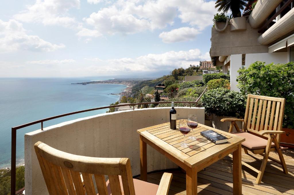 un tavolo e sedie su un balcone con vista sull'oceano di Eurostars Monte Tauro a Taormina