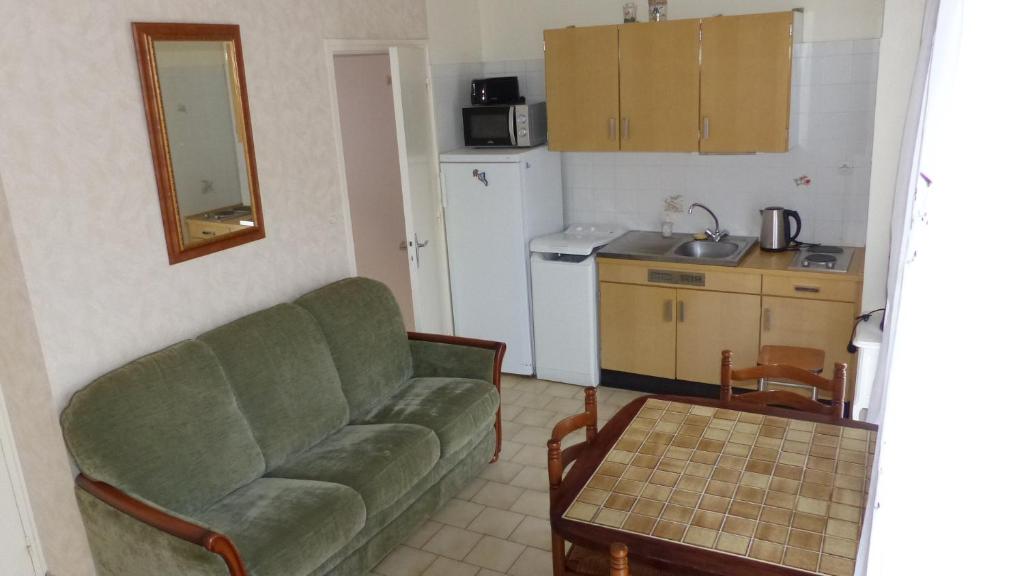a living room with a green couch and a kitchen at PIED A TERRE 4 in Amélie-les-Bains-Palalda