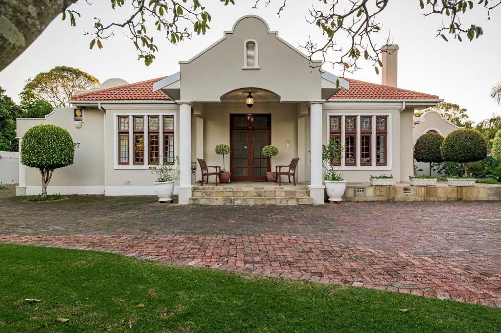 a large white house with a brick driveway at Millbury Guest House in Port Elizabeth