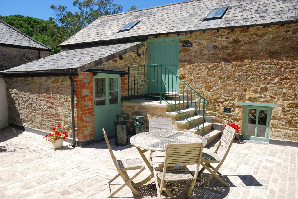 a patio with a table and chairs in front of a building at Granary at Trewerry Cottages - Away from it all, close to everywhere in Newquay