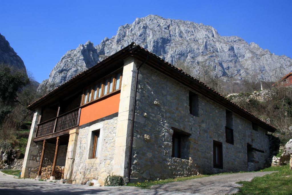 a stone building with a mountain in the background at Hotel Rural Llerau in Taranes