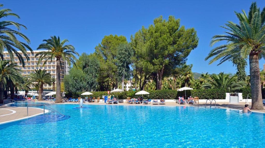 una gran piscina con palmeras y un hotel en Sol Palmanova All Inclusive, en Palmanova