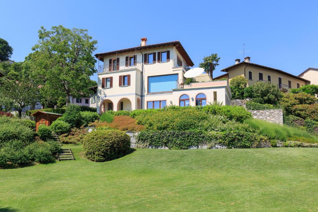 una grande casa su una collina con un cortile di Villa Rubino Apartment con giardino e jacuzzi vista lago a Stresa