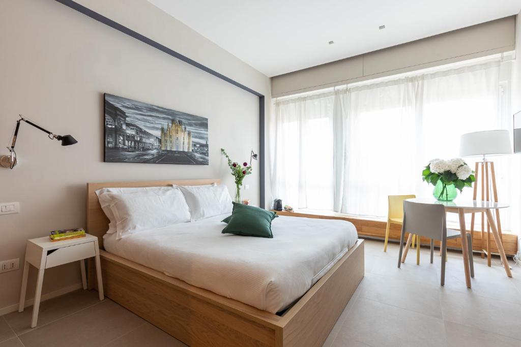 a bedroom with a large bed with a table and a window at BePlace Garibaldi Suites in Milan
