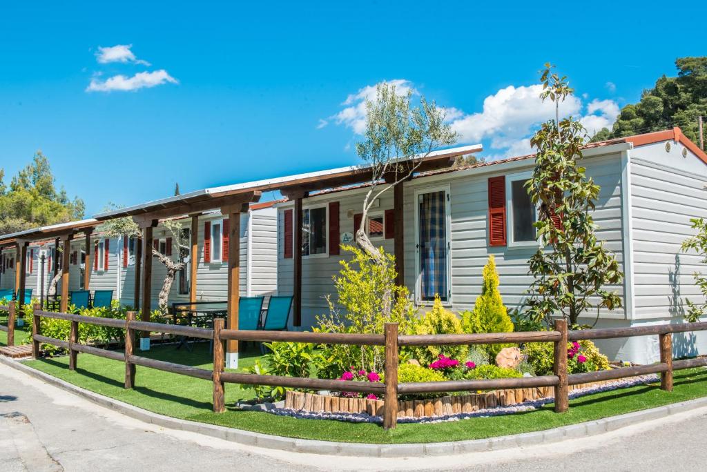 une maison avec une clôture et des fleurs devant elle dans l'établissement Camping Castello, à Neos Marmaras