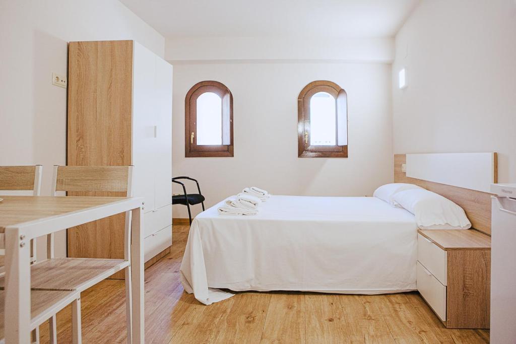a white bedroom with a bed and a table at Apartamentos Ducay in Olite