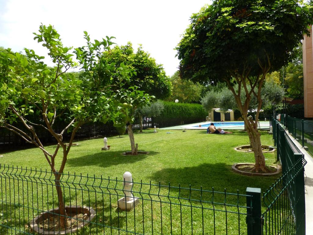 una recinzione di fronte a un cortile alberato e a una piscina di Milenium Palace - Garaje incluido - Piscina-FIBES a Siviglia