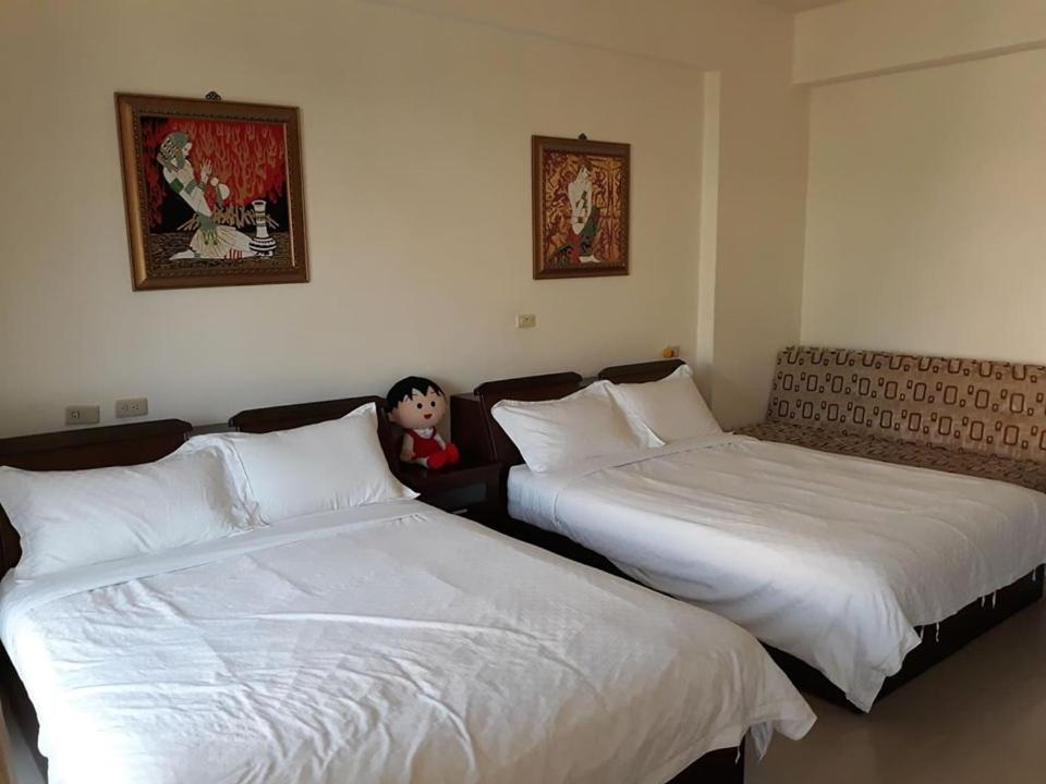 a man sitting between two beds in a hotel room at Star 101 Guest House in Taitung City