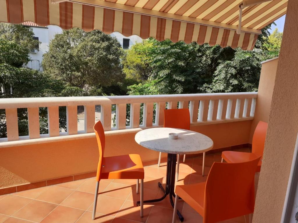 a patio with a table and chairs on a balcony at Apartmani Ruža in Novalja