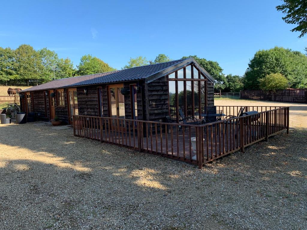 a wooden cabin with a fence in a yard at Stable lodge 2 Bedrooms in Horspath
