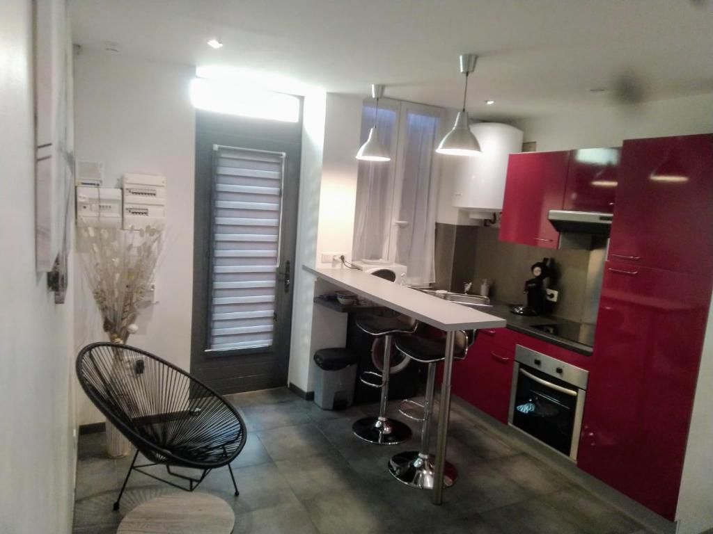 een keuken met rode kasten en een zwarte stoel bij Aux portes de l'Eure in Bonnières-sur-Seine