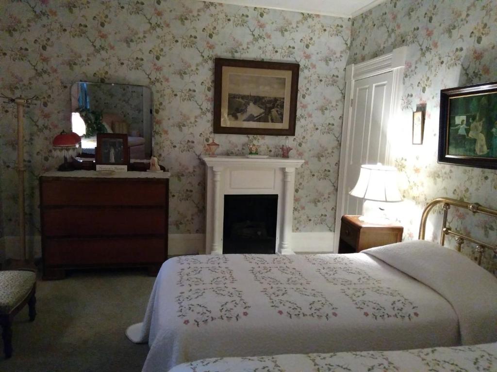 - une chambre avec un lit et une cheminée avec du papier peint dans l'établissement Couture Farm at Millstone Hill, à Barre