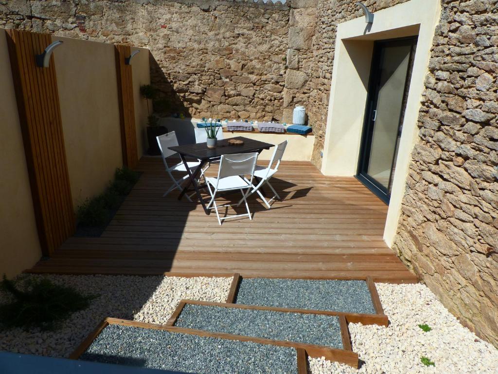 une terrasse en bois avec une table et des chaises dessus dans l'établissement Le Stepharion, à La Gaubretière