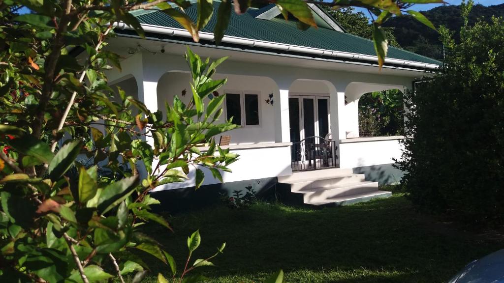 ein weißes Haus mit grünem Dach in der Unterkunft Destination Self-Catering in Grand'Anse Praslin