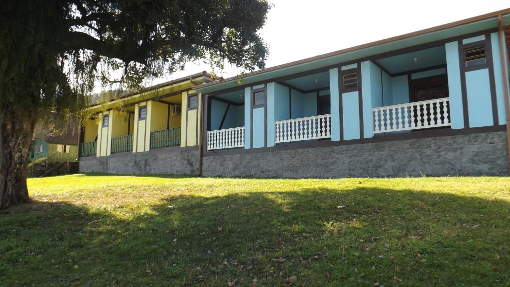 un edificio amarillo y azul con un árbol delante de él en Recanto dos Pioneiros, en Nova Petrópolis
