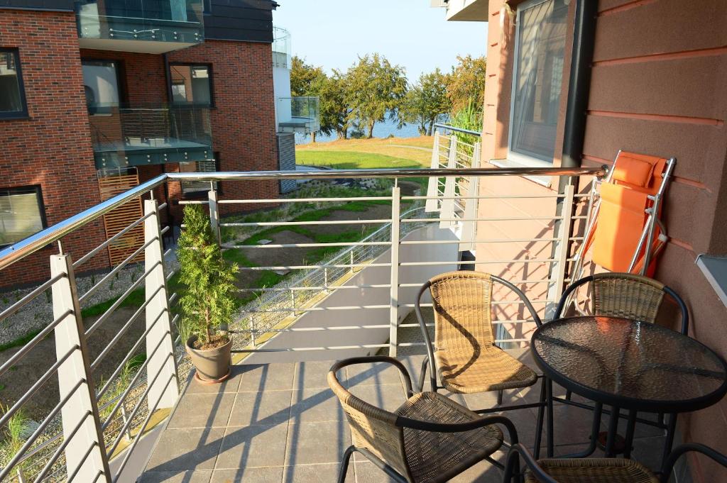 a balcony with three chairs and a table and a plant at Apartament Babitonga I in Puck