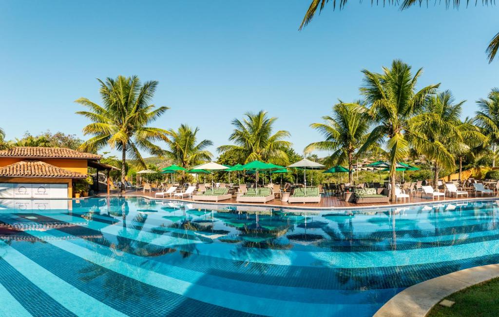 uma piscina no resort com cadeiras e guarda-sóis em Hotel Ferradura Resort em Búzios