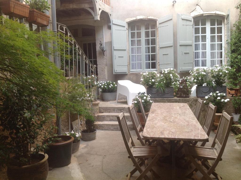 un patio con mesa, sillas y plantas en Les Chambres de L'Horloge, en Lectoure
