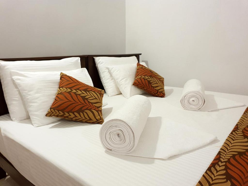 ein weißes Bett mit Handtüchern und Kissen darauf in der Unterkunft A and D Holiday Inn in Anuradhapura