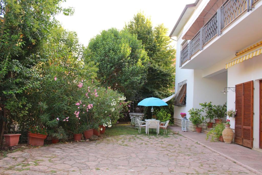 un patio con una mesa y una sombrilla azul en A Casa di Elisabetta, en Santa Maria degli Angeli