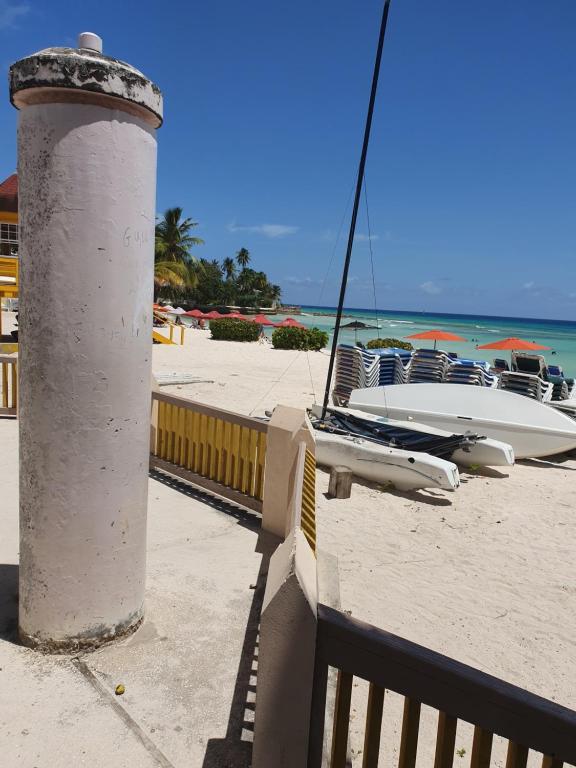 a lighthouse on the beach with a boat on the sand at Breezy Apts in Saint Philip