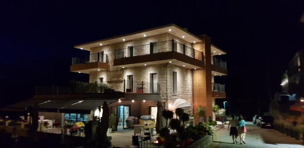 Un bâtiment avec des personnes debout à l'extérieur le soir dans l'établissement Hotel Le Tourisme, à Zonza