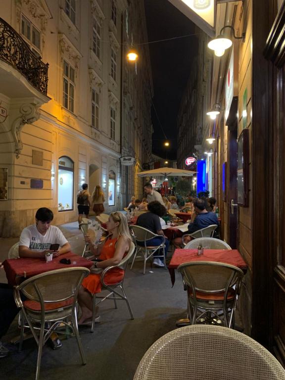 a group of people sitting at tables at an outdoor restaurant at KH Apartments Stephansplatz in Vienna