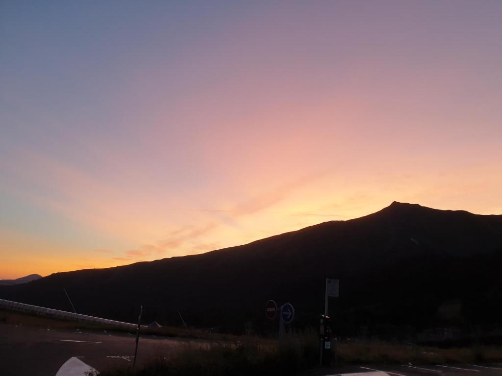 un coucher de soleil avec une montagne en arrière-plan dans l'établissement Résidence azur sancy, à Le Mont-Dore