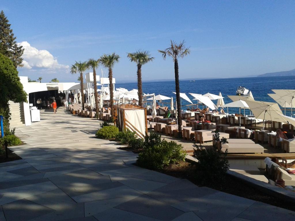 plaża z krzesłami i palmami i oceanem w obiekcie Studio Apartment Vanna - 1st row to the sea w mieście Opatija