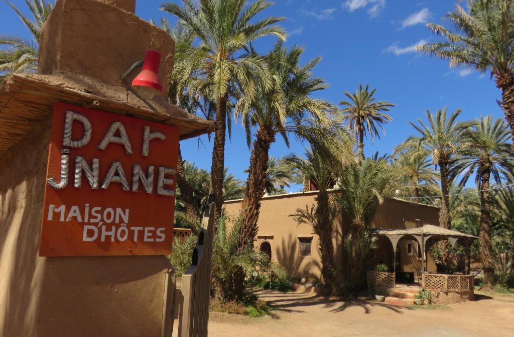 a sign for a restaurant in front of palm trees at Dar Jnane - La Maison Du Jardin in Agdz