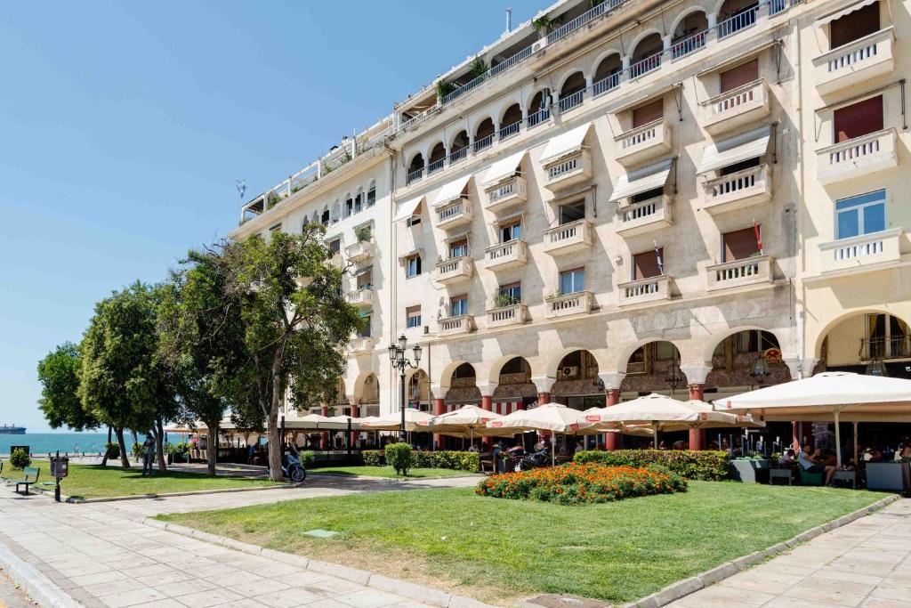 a large building with tables and umbrellas in front of it at Square Elegant Suites in Thessaloniki