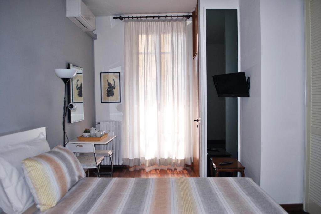 米蘭的住宿－A Milàn B&b，一间卧室配有一张床、一张书桌和一个窗户。