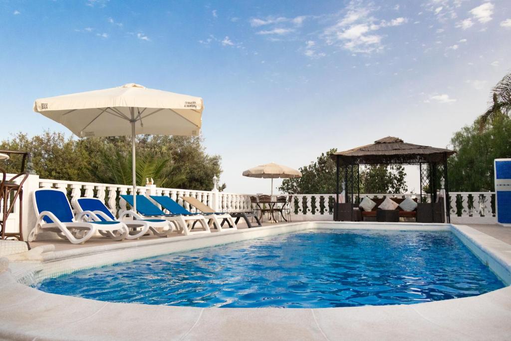 a swimming pool with chairs and an umbrella at La Finca del Morro in San Miguel de Abona