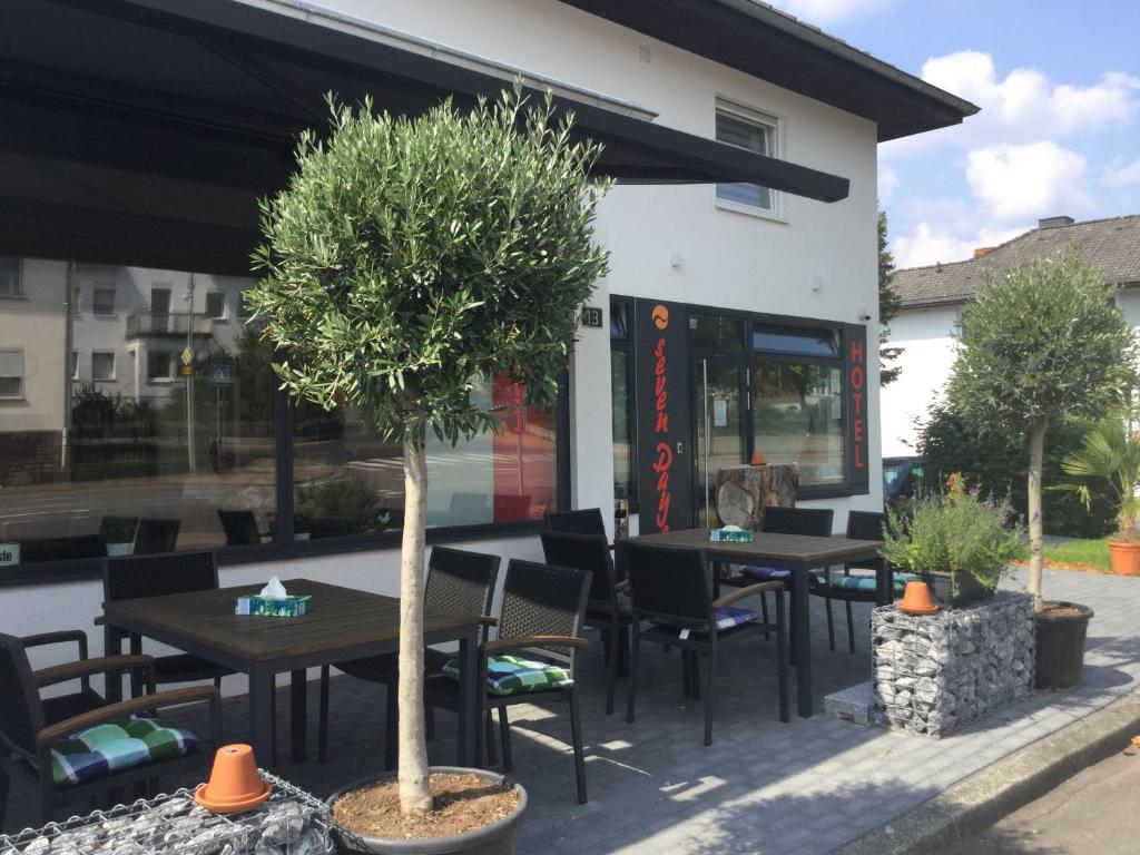 a restaurant with tables and chairs and a tree at sevenDays Hotel and Boardinghouse Kirchheim in Kirchheim