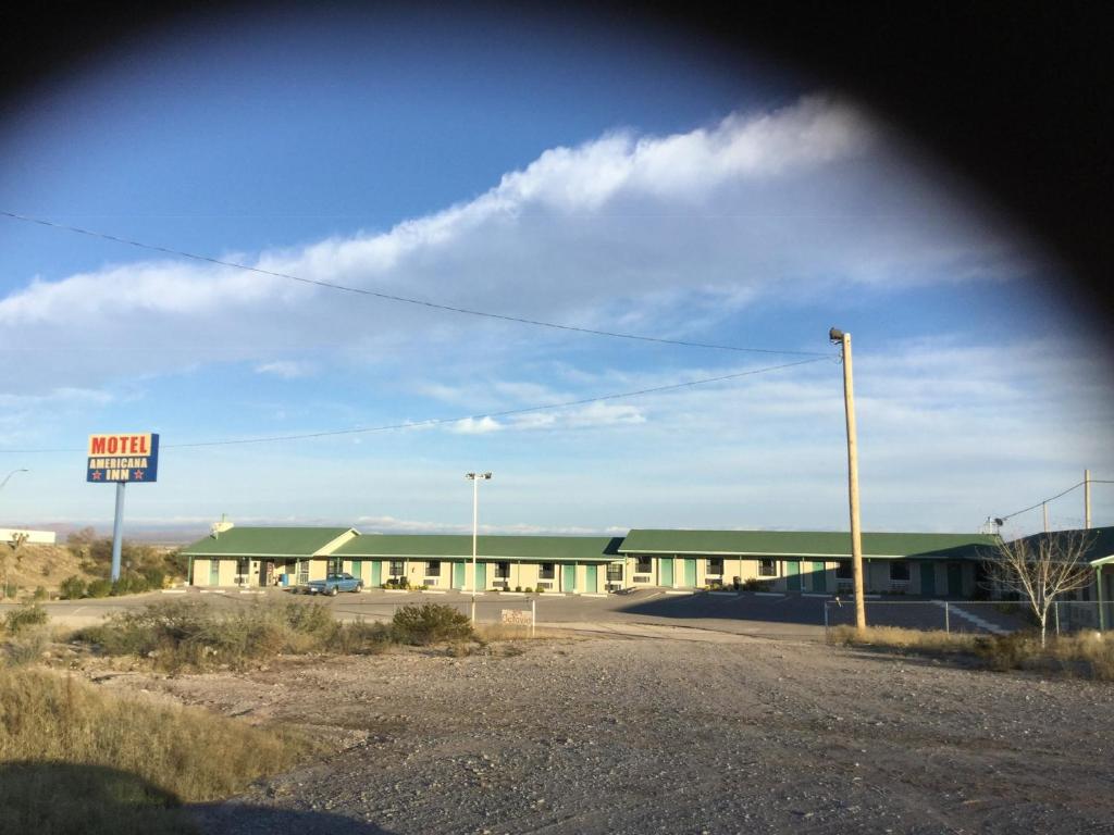 un grand bâtiment avec un panneau devant lui dans l'établissement Americana Inn, à Sierra Blanca