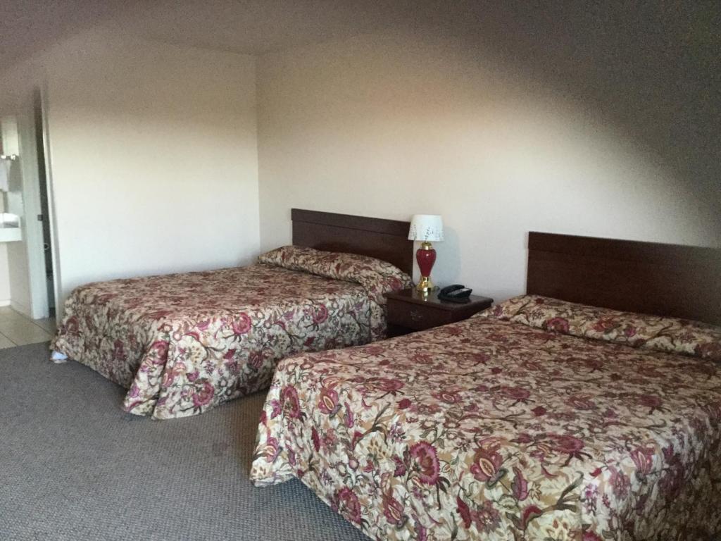 a hotel room with two beds and a lamp at Americana Inn in Sierra Blanca