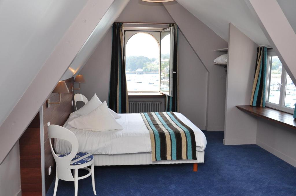 a attic bedroom with a bed and a window at Hôtel des Rochers in Perros-Guirec
