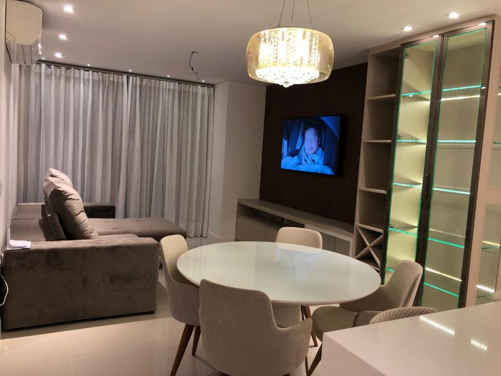 a living room with a table and a couch and a tv at Gramado - Centro - Apto Novo in Gramado