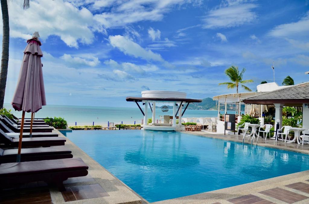 a swimming pool with an umbrella and the ocean at Al's Resort in Chaweng