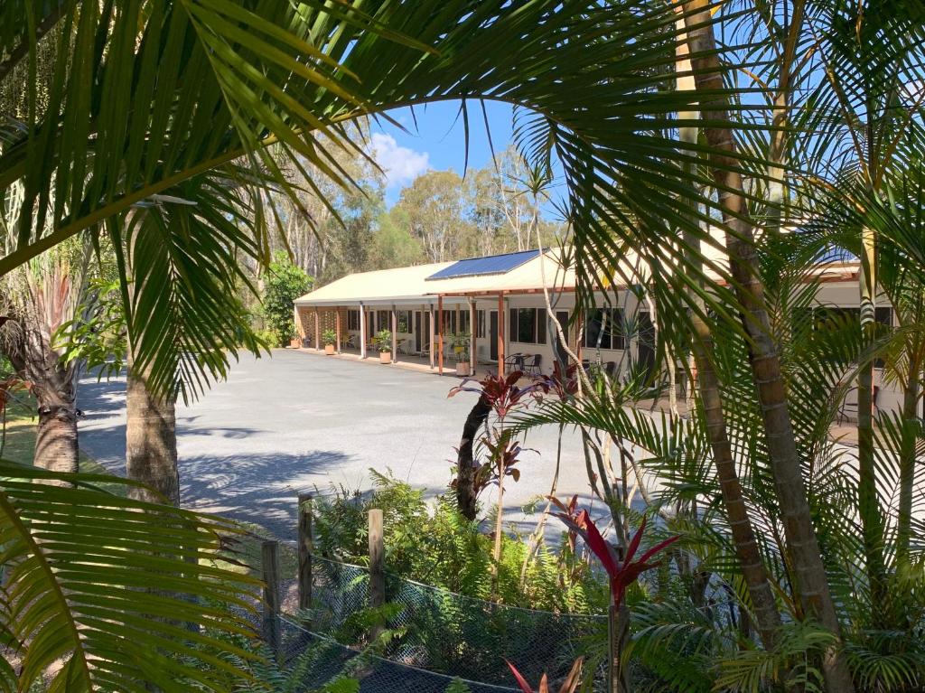 a building with a lot of palm trees in front of it at Tin Can Bay Motel in Tin Can Bay