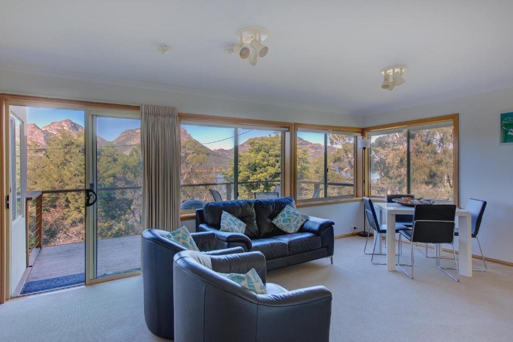 a living room with couches and a table and chairs and windows at Freycinet Sanctuary 5 in Coles Bay