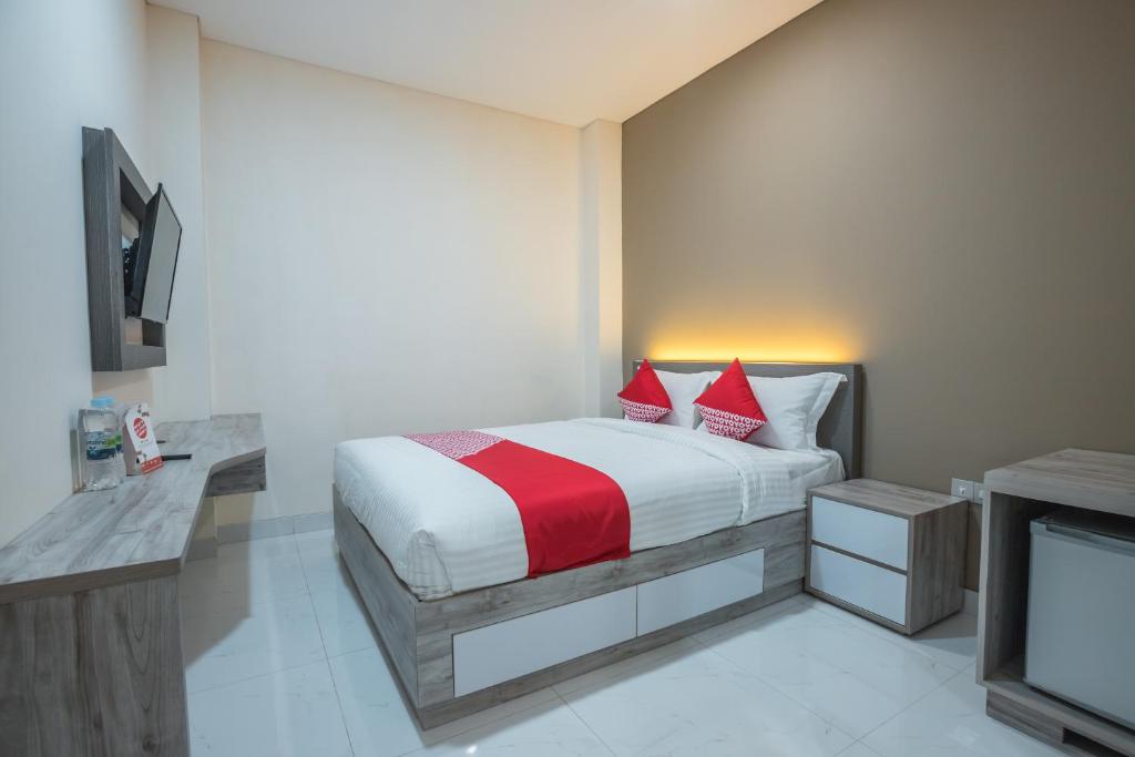 a bedroom with a bed with red pillows and a tv at Super OYO 1487 Residence Khoe in Jakarta